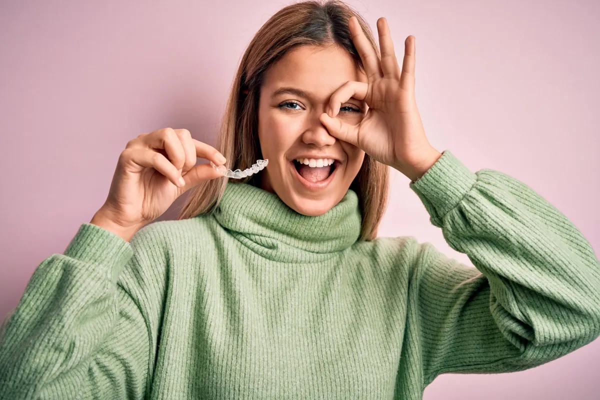 Happy woman holding a clear aligner